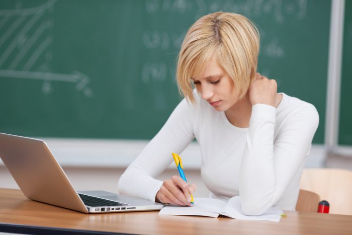 female student writing concentrated in the classroom
